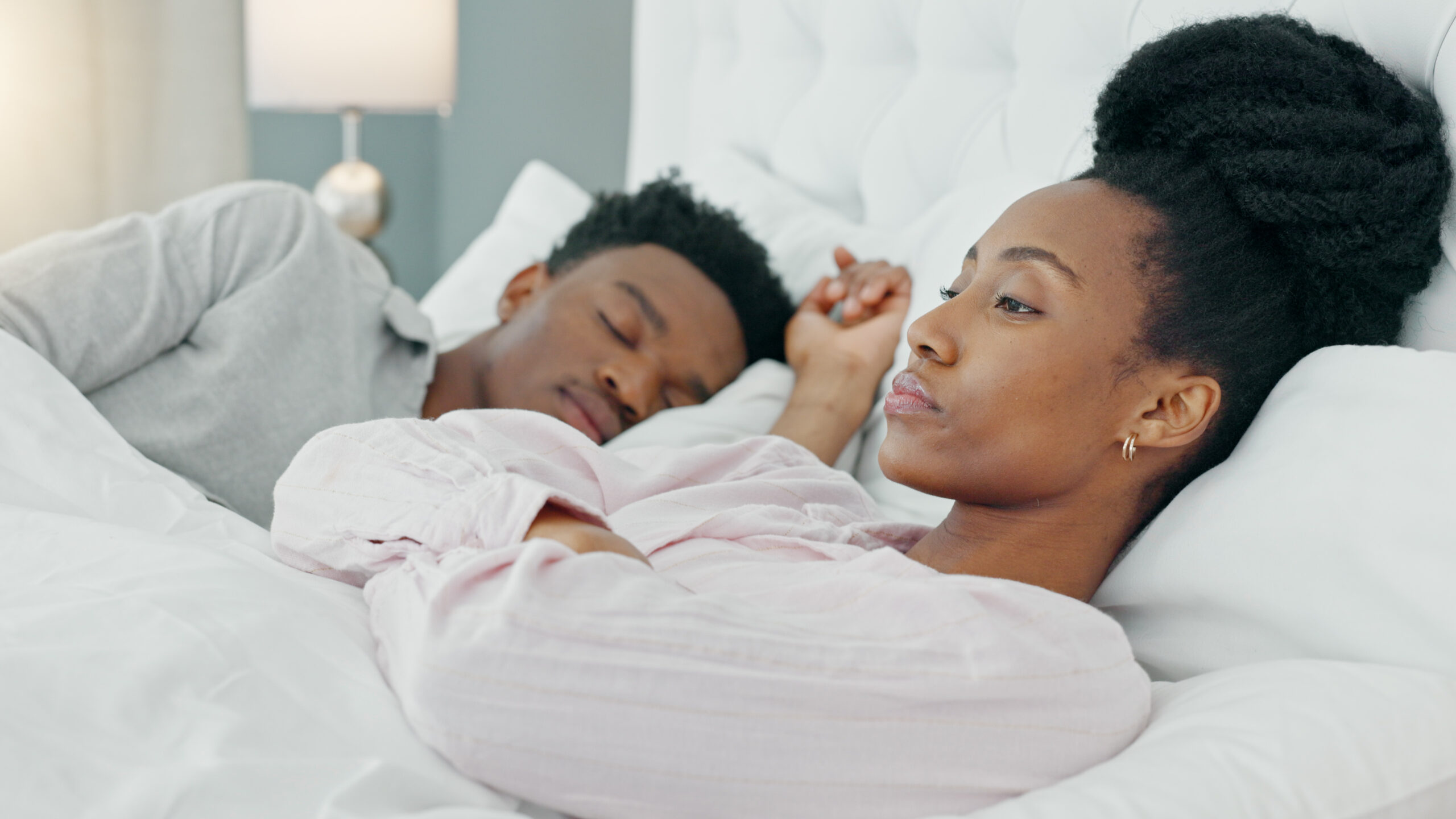 Insomnia, couple and black woman in bed frustrated by snoring, crisis or sleep apnea at home. Sleeping, conflict and angry female with stress, anxiety or divorce depression, liar or bedroom problem