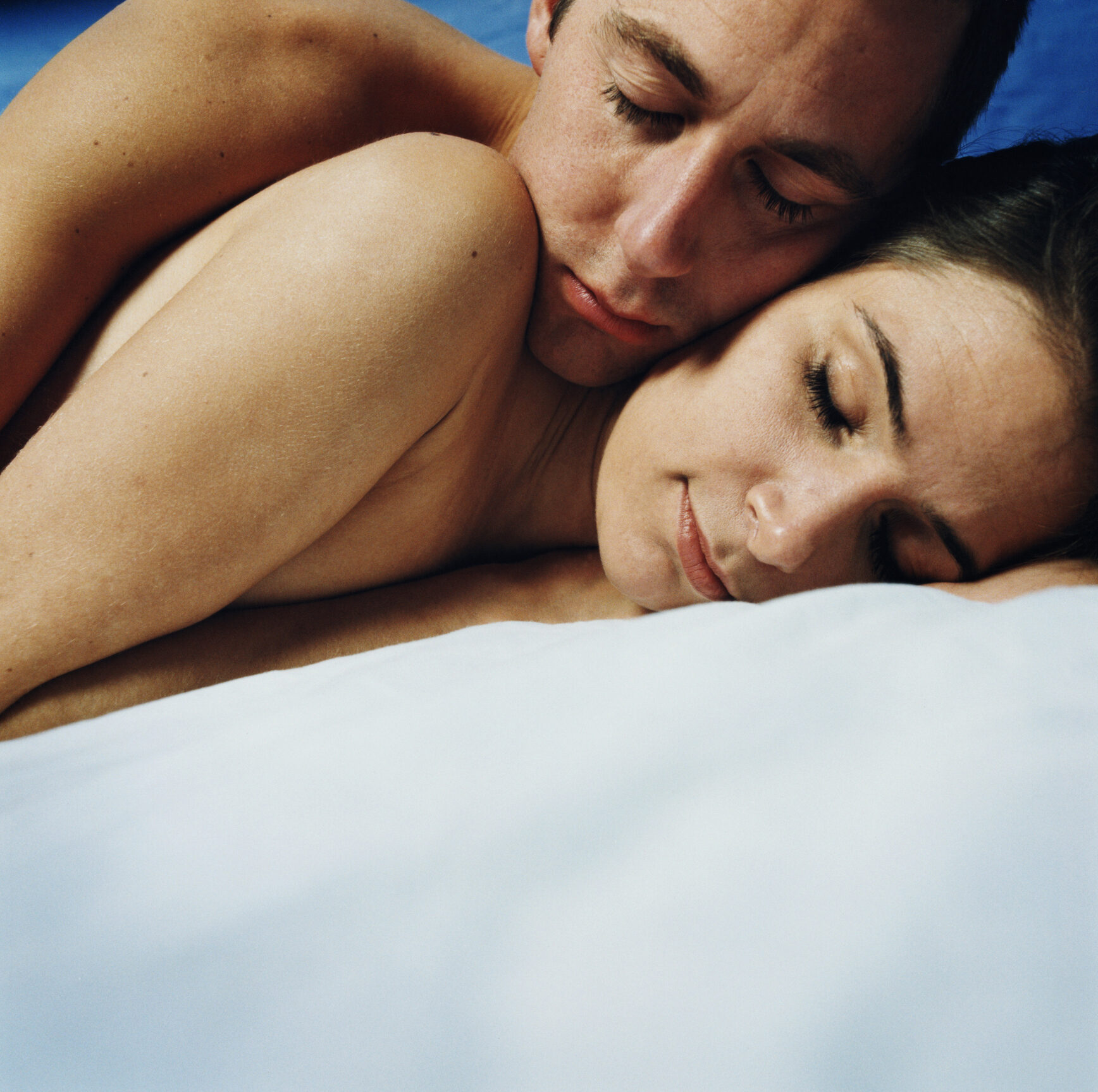 Naked young couple asleep, embracing, close-up