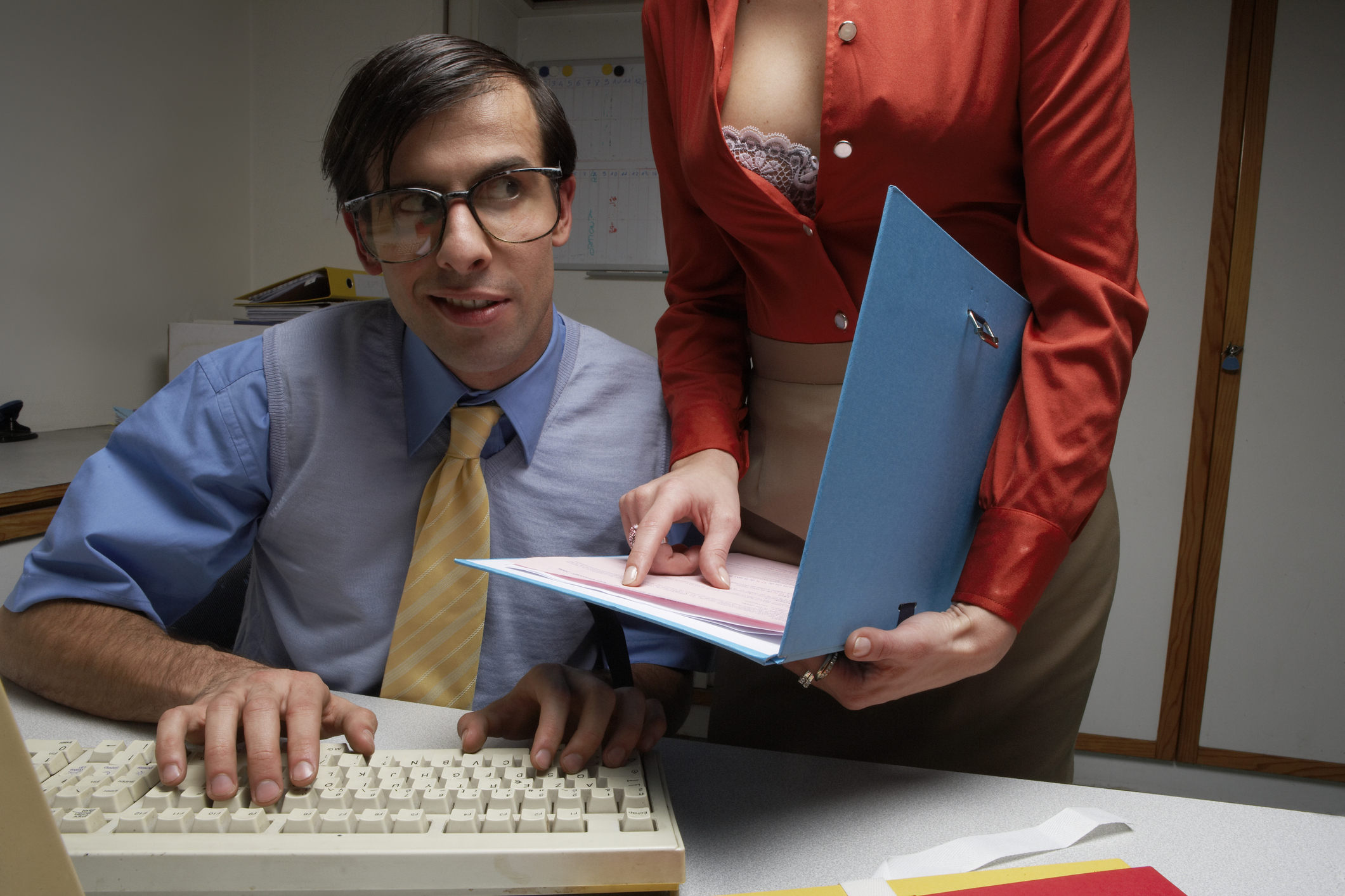 Male office worker being shown file by colleague with shirt unbuttoned