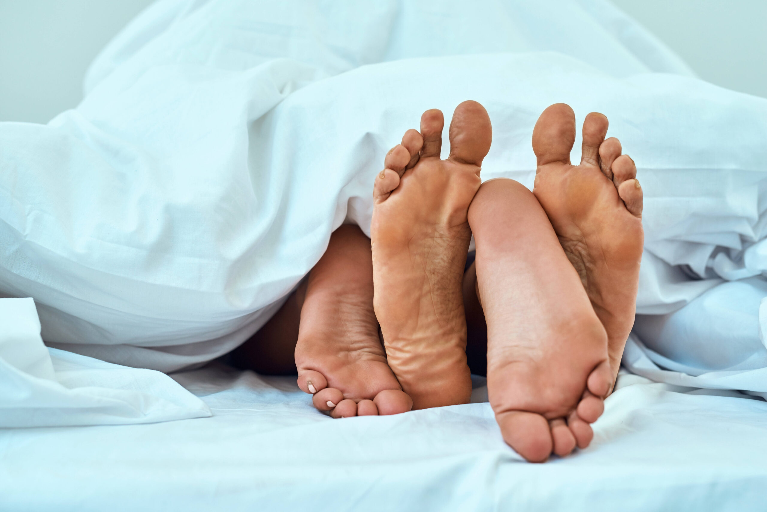 This is exactly where I belong. a couples feet poking out from under the bed sheets. Sex scheduling
