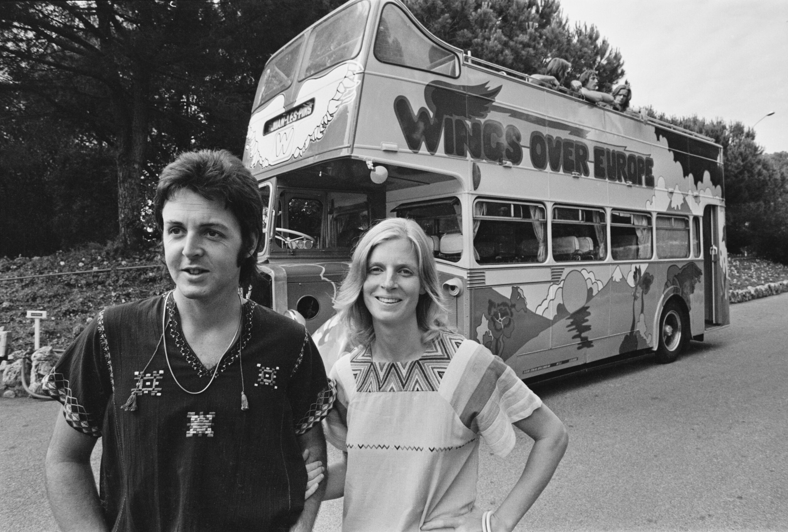 Paul McCartney and American photographer and musician Linda McCartney (1941-1998) in front of the converted bus in which their band Wings 